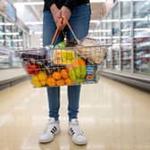 A woman holds a basket of goods in a supermarket.