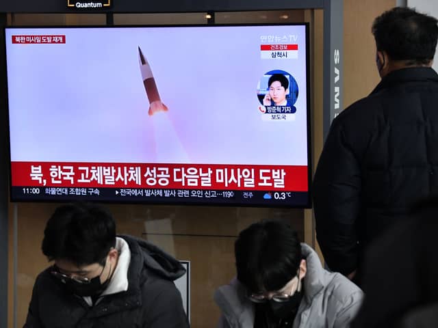 A man watches a television screen showing a news broadcast with file footage of a North Korean missile test, at a railway station in Seoul on December 31, 2022