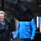 A woman battles to keep control of her umbrella as she walks through a rain shower in Glasgow.