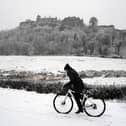 A person rides a bicycle in the snow at Stirling Castle.
