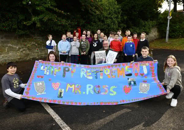 Eric Ross MBE, pictured centre, with pupils at his delayed retirement presentation last week at Grange Primary. Photo by Michael Gillen.