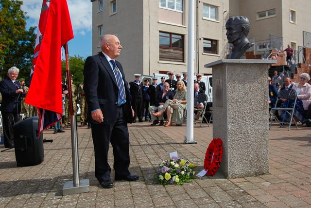 William McAleese lays flowers at the memorial bust of his twin brother John