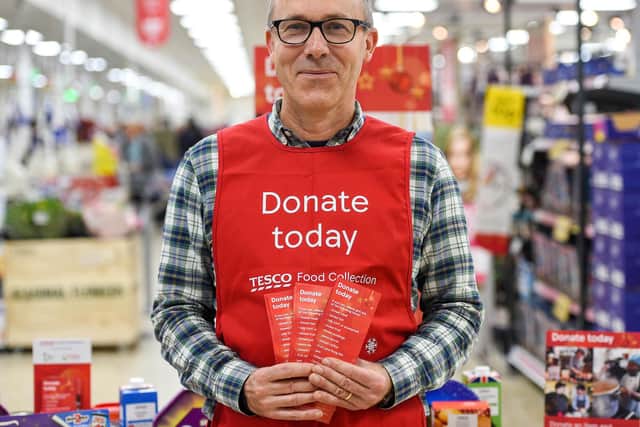 A Tesco volunteer holding a shopping list guide for donations at the launch of the Tesco Food Collection