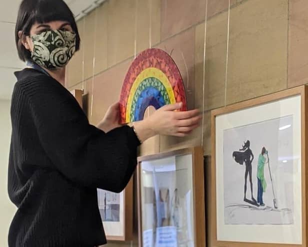 Silvia Sinibaldi, visual arts assistant curator with Artlink Central, hangs the Damian Hirst print on the Rainbow Wall at Forth Valley