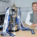 Sean Mackie pens his new Falkirk deal next to the League One trophy (Photo: Ian Sneddon)