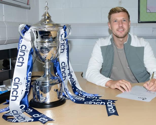 Sean Mackie pens his new Falkirk deal next to the League One trophy (Photo: Ian Sneddon)