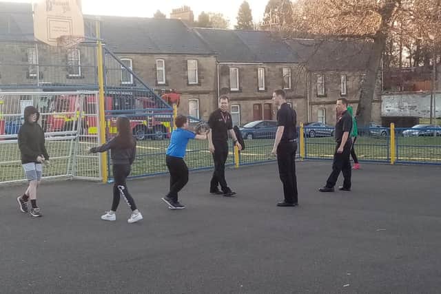 Firefighters enjoy some fun with youngsters on the basketball court at a Twilight Sports session