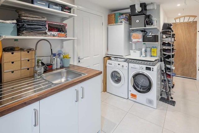 A spacious and multipurpose utility room houses the laundry appliances and provides ample storage for jackets, shoes and school bags.