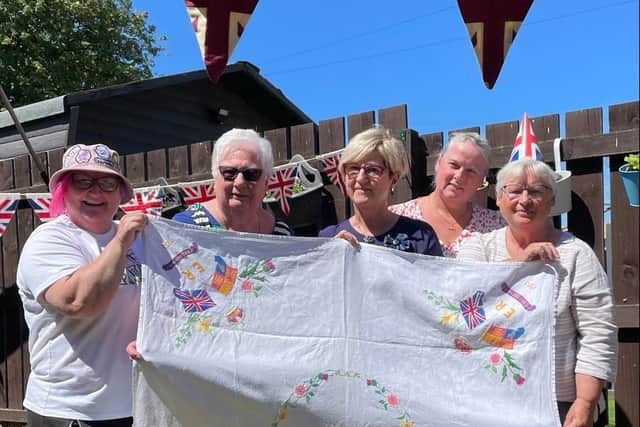 Members of the Somerville family celebrating the Jubilee Tea Party with Coronation tablecloth embroidered by their motherand grandmother for the Queen’s Coronation in 1953.