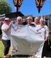 Members of the Somerville family celebrating the Jubilee Tea Party with Coronation tablecloth embroidered by their motherand grandmother for the Queen’s Coronation in 1953.