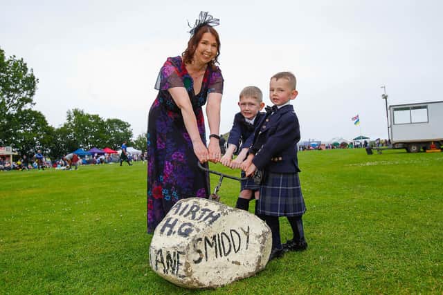 Last year's Airth Highland Games, chieftain Sharon Ritchie, head teacher at Airth Primary, with her sons Jake (7) and Harris (5) attempting to lift the Smiddy Stane. Pic: Scott Loudon