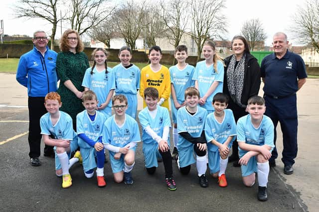 Pictured with the pupils from P5, P6 and P7 in the new strips are: David Hume, product consultant Arnold Clark Falkirk Fiat; Ailidh Hutt, acting deputy headteacher; Gill Mullan, warranty administrator Arnold Clark Falkirk Fiat and Larry Mullan, school janitor.  (Pic: Michael Gillen)