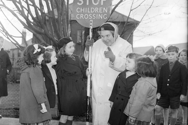 Patrol woman Mollie Harris helps children cross the road at Oxgangs in February 1962.