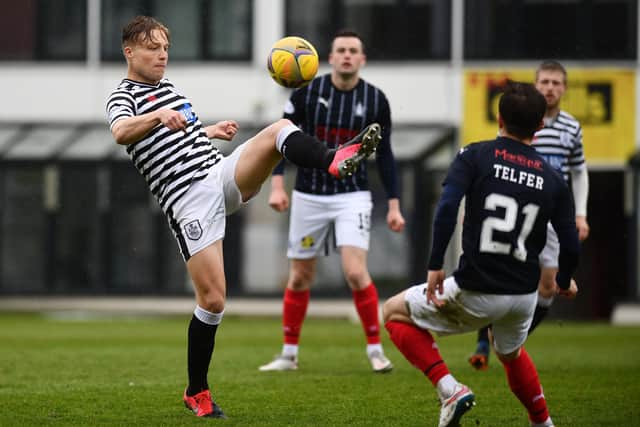 Peter Grant clears the ball with Charlie Telfer looking to close in