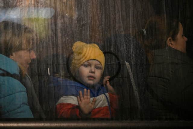 A child greets from the window of a bus after crossing the Ukrainian border with Poland at the Medyka border crossing. (Pic: LOUISA GOULIAMAKI/AFP via Getty Images)