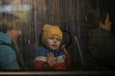 A child greets from the window of a bus after crossing the Ukrainian border with Poland at the Medyka border crossing. (Pic: LOUISA GOULIAMAKI/AFP via Getty Images)