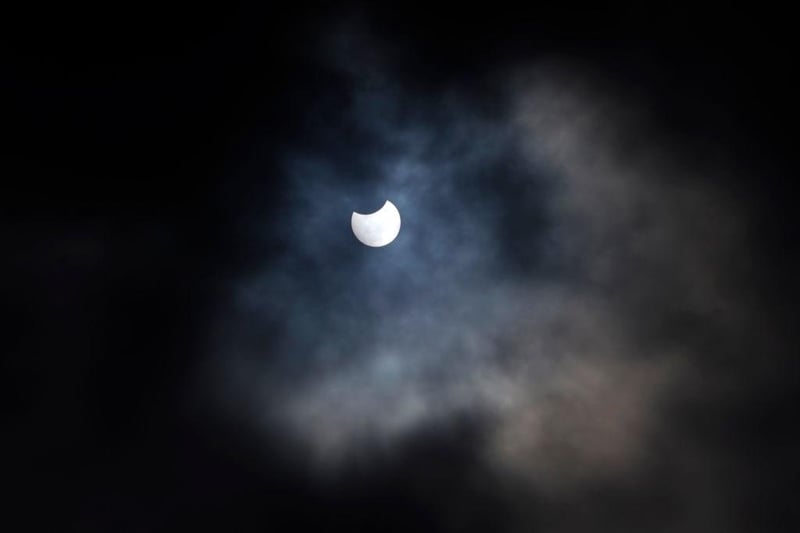 A partial solar eclipse is seen through cloud cover from Primrose Hill in central London on June 10, 2021