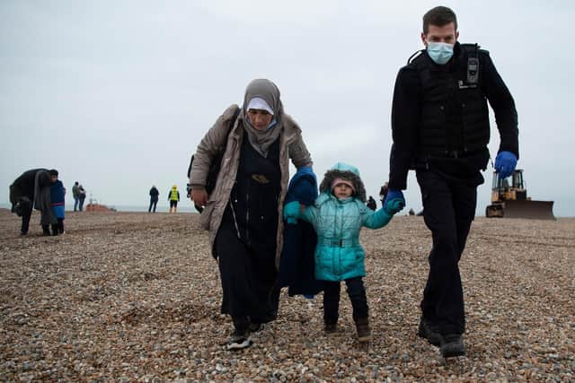 A member of the UK Border Force  helps migrants on a beach in Dungeness on the south-east coast of England (Pic: Ben Stansall/AFP via Getty Images)
