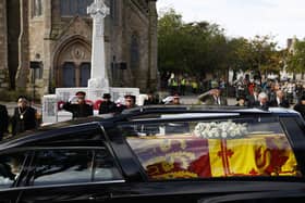 A salute from crowds gathered to pay tribute as the coffin of the late Queen Elizabeth travels through Ballater (Photo by Jeff J Mitchell/Getty Images)