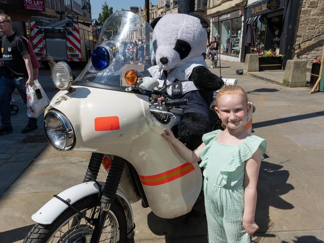 A youngster smiling in front of a vintage police motorcycle.