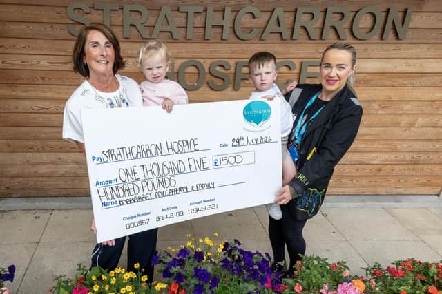 Margaret McCafferty with her grandchildren, Hope and Luke Egan, hand over a cheque for £1500 to Amy Petale, Strathcarron fundraising assistant. Pic: Michael Gillen