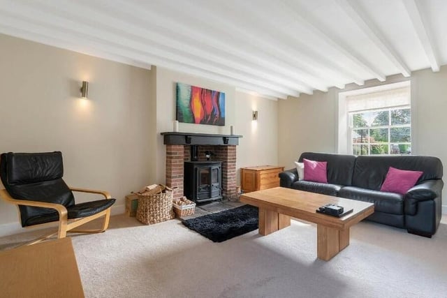 The spacious living room, with feature beamed ceiling, has a wood burning stove and brick fireplace as its focal point.