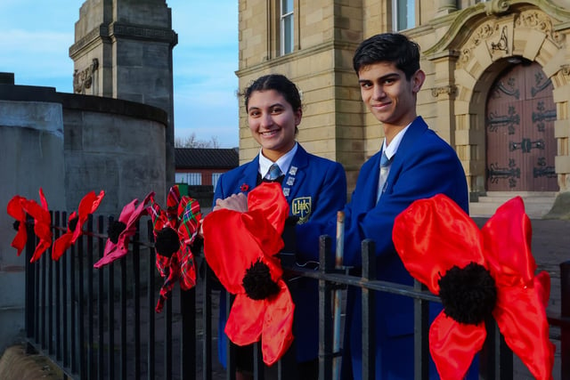 Larbert High School S6 pupils Kiran Chadha and Cameron Simmons with some of the ten poppies created by pupils, one poppy to represent each decade of remembrance at Larbert's War memorial
