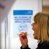 A woman uses a swab to take a sample from her mouth at a NHS Test and Trace Covid-19 testing unit. Photo by ADRIAN DENNIS/AFP via Getty Images