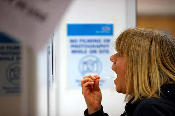 A woman uses a swab to take a sample from her mouth at a NHS Test and Trace Covid-19 testing unit. Photo by ADRIAN DENNIS/AFP via Getty Images