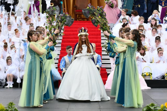 Queen Sophie Rutherford walks through a bower of flowers.