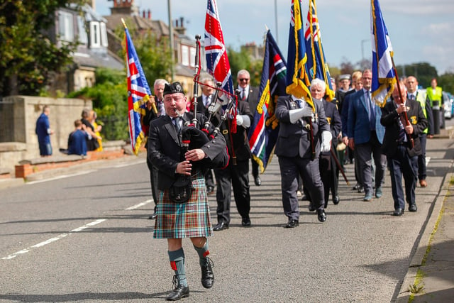 A piper leads the parade through the streets of Laurieston