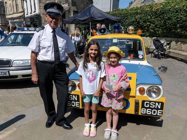 A photo in front of a vintage police vehicle.