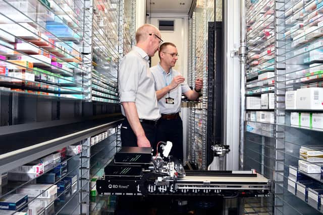 NHS Forth Valley CEO Ross McGuffie and Derek Brown Pharmacy Support Workers PSW team leader give new robots Duke and Baron a hand in the pharmacy. Pic: Michael Gillen