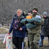 A Polish soldier carries a child and helps a refugee family after they crossed the border into Poland from Ukraine (Photo by LOUISA GOULIAMAKI/AFP via Getty Images)