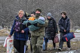 A Polish soldier carries a child and helps a refugee family after they crossed the border into Poland from Ukraine (Photo by LOUISA GOULIAMAKI/AFP via Getty Images)