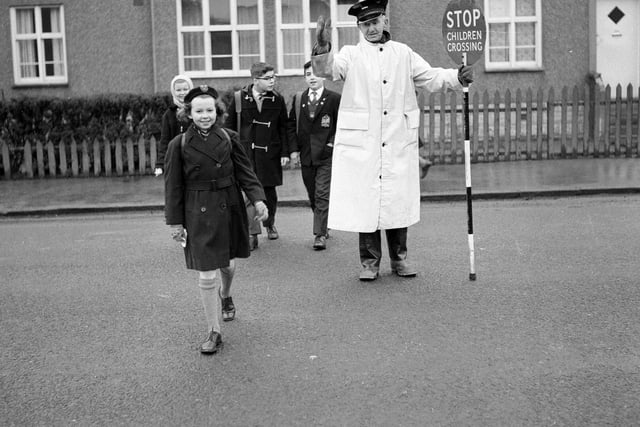 Traffic warden and lollipop man William Withnell shows children across the Colinton Mains Road to Oxgangs Primary School in 1963.