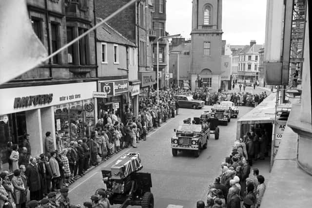 Pedestrians stop in silent tribute as the coffins of two part-time paratroopers killed in the River Trent disaster are carried through Falkirk High Street in October 1975