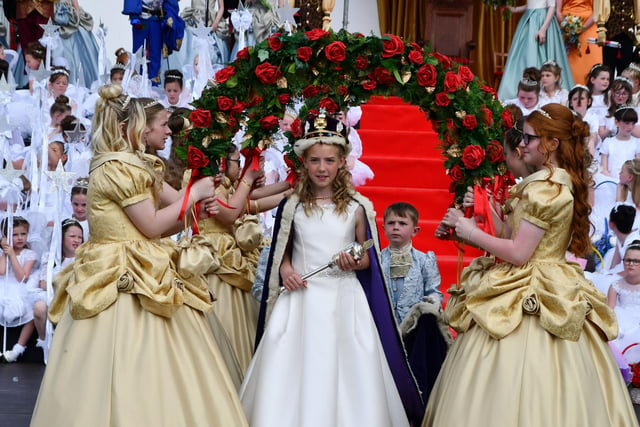 Queen Aimee walks through a bower of roses to be presented to her subjects