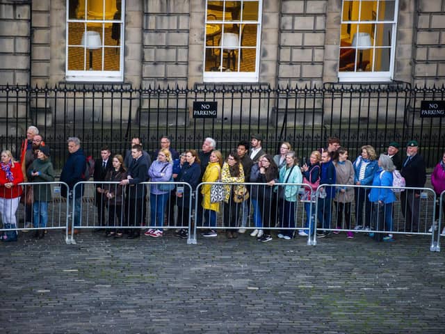 Members of the public stand outside waiting to pay their respects.