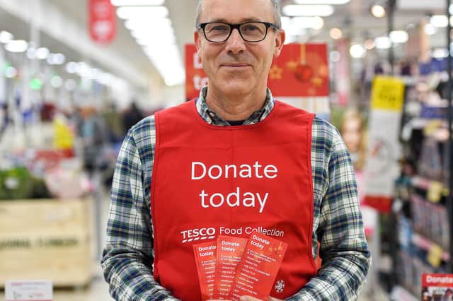 A Tesco volunteer holding a shopping list guide for donations at the launch of the  festive campaign