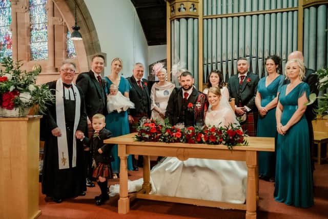 Elise Thomson and Thomas Peden sign the register after their marriage in Stenhouse and Carron Church surrounded by the family and the wedding party