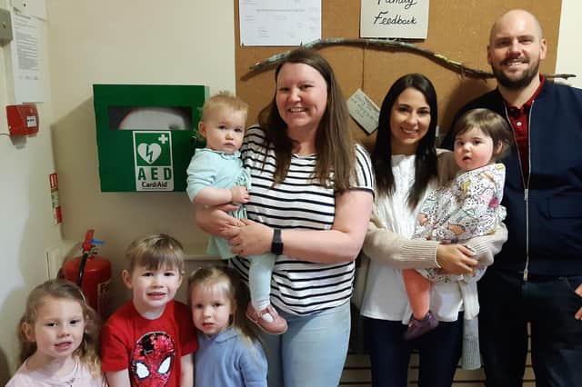 Youngsters at Cherry Tree Nursery in Polmont with the newly installed defibrillator.  Pictured are nursery manager Cheryl Connell, Gemma and Ross Kennedy with daughter Mia, and some of the youngsters at the nursery.