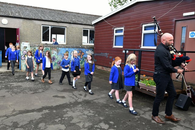 Music teacher Cameron Nisbet pipes the pupils out of the school.