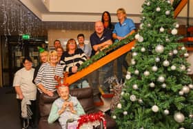 Resident Margaret, front, gets into the Christmas spirit around the tree with staff.