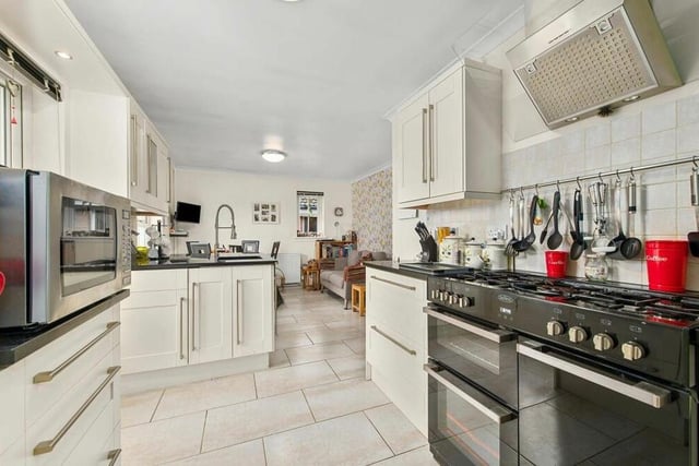 The contemporary kitchen/diner boasts integrated appliances and an array of cupboard units and drawers.