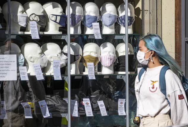 A woman wearing a protective face mask walks past a shop selling masks. Is the prospect of restrictions being lifted making you feel apprehensive?