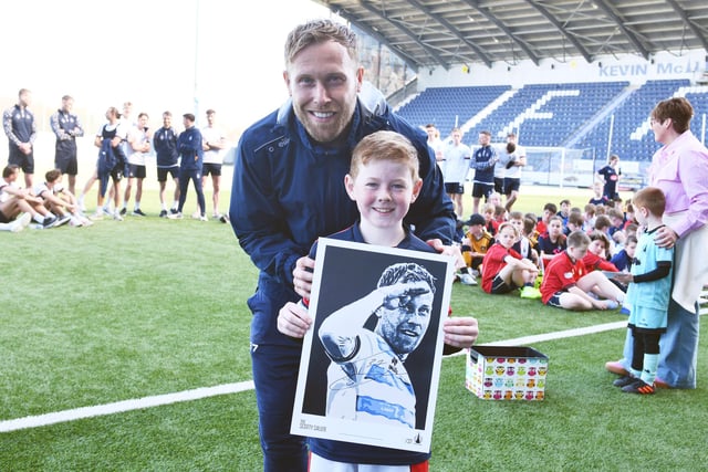 Falkirk star Scott Arfield poses with a young Junior Bairn member who won a special signed poster