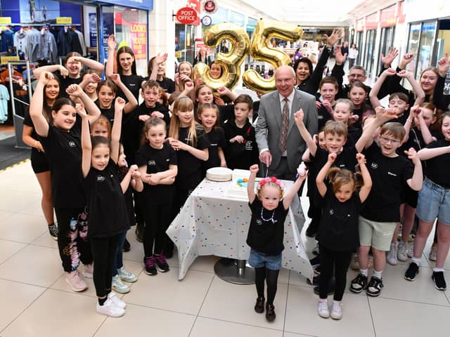 Alex Totten does the honour by cutting the Howgate's 35th birthday cake with help from Project Theatre youngsters.