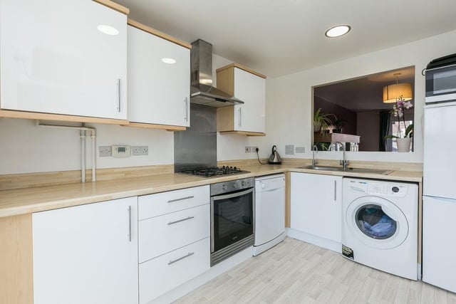 The kitchen is fitted with modern units, wood effect worktops with matching upstands, sink with drainer, and an integrated gas hob, extractor hood and oven.