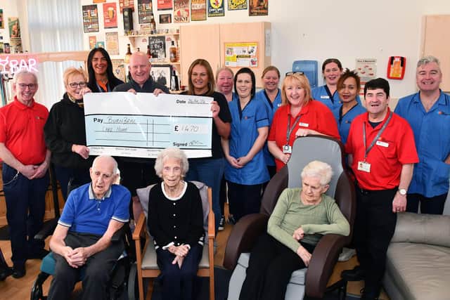 Bungee jumper Neil Hall hands over the cheque to Burnbrae Home with Carronshore bar licensee Kate Dempster along with bar staff Melissa Garrity, watched by staff and residents. Pic: Michael Gillen